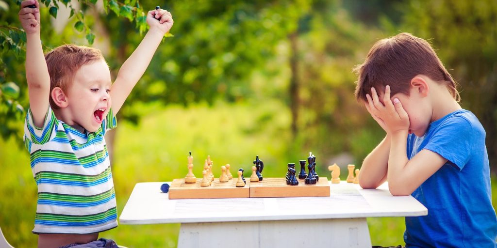 two boys playing chess, one has just won the game and is celebrating