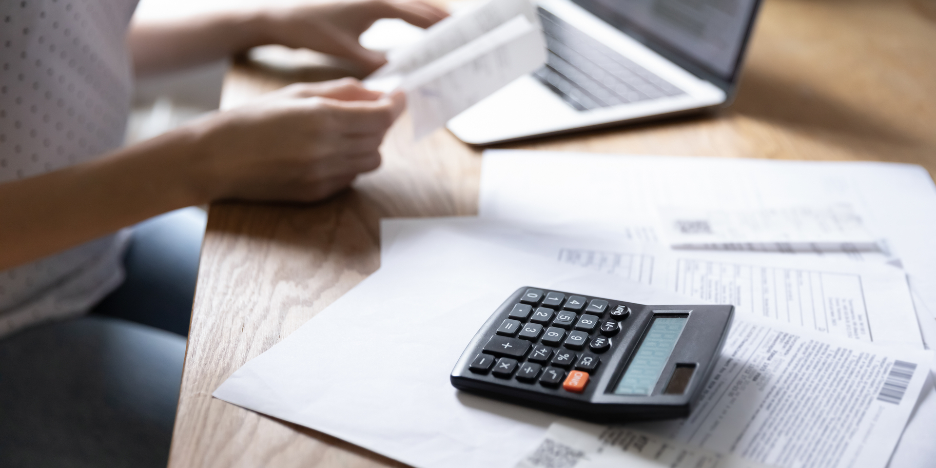 Close up of a woman sitting at her desk managing household expenses and paying bills on her laptop.