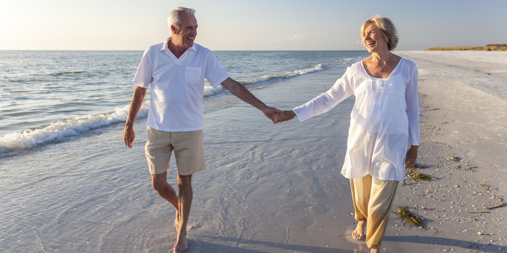 Happy senior couple walking on beach